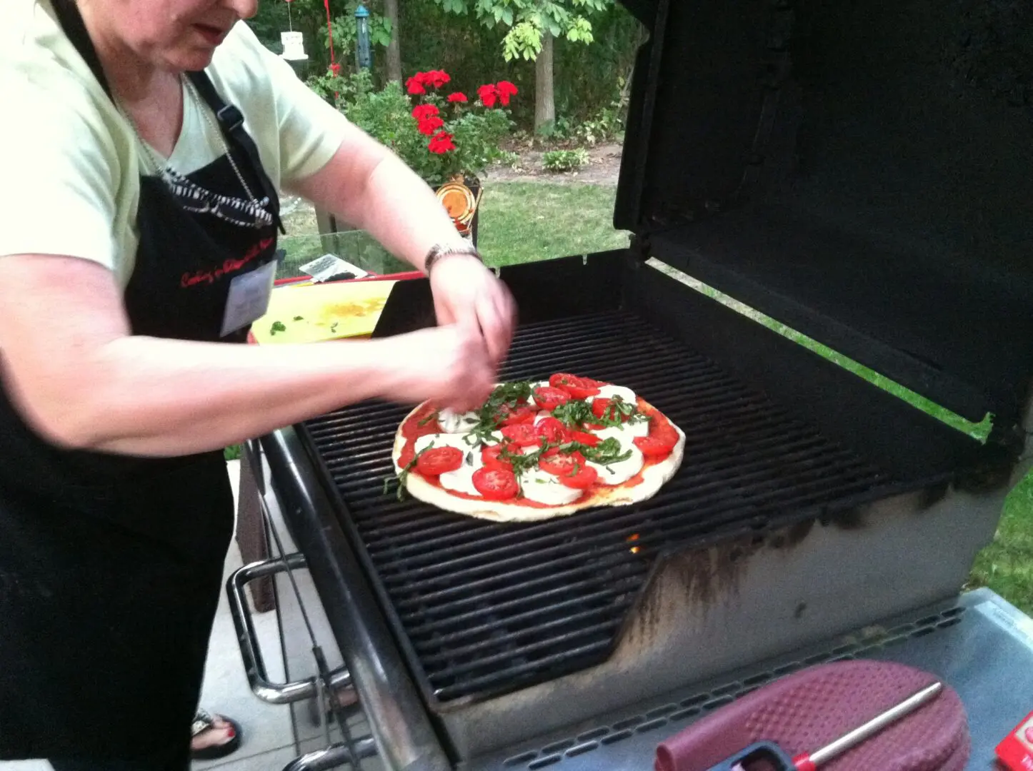 A woman cooking pizza on grill