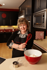 A woman participating in team-building cooking classes is wearing a black apron.