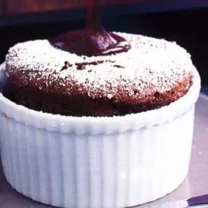 A chocolate souffle on a plate with powdered sugar.