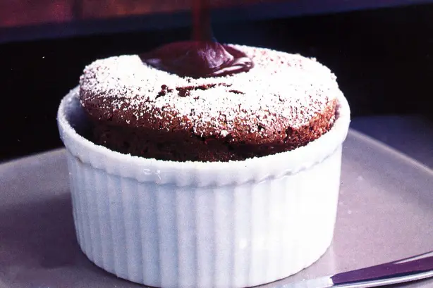 A chocolate souffle on a plate with powdered sugar.