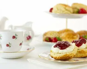 Scones with jam and a cup of tea on a white background.