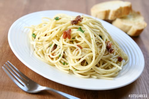 Spaghetti with bacon and bread on a plate.