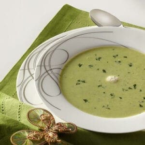 A bowl of green soup on a green napkin.