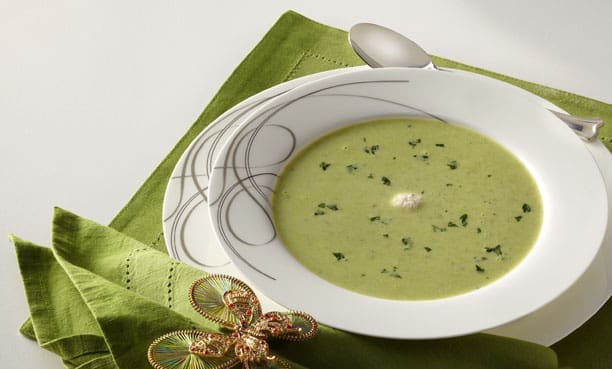 A bowl of green soup on a green napkin.