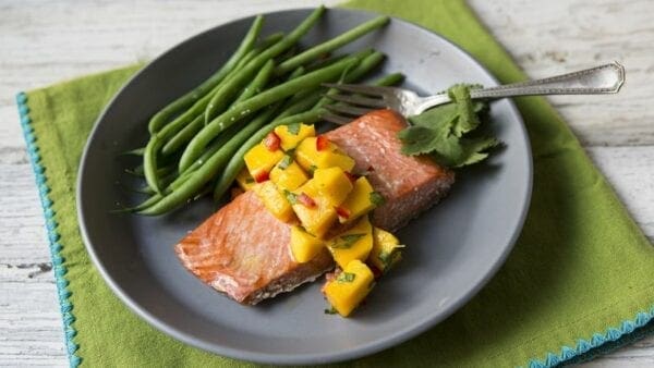 Salmon with mango salsa and green beans on a plate.