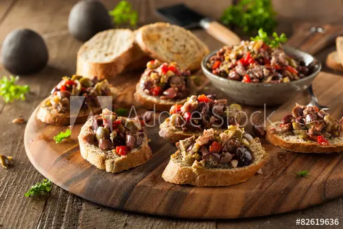 Bruschetta with olives and peppers on a wooden board.