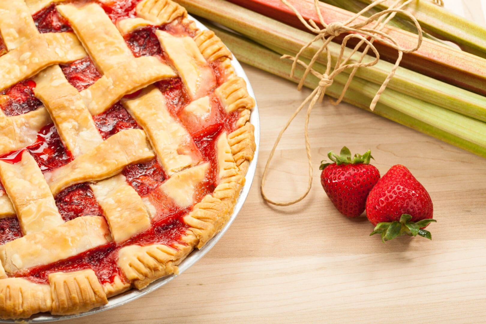 A pie with strawberries and rhubarb on a wooden table.