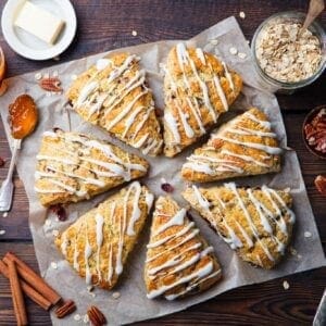 Scones with icing and nuts on a wooden table.