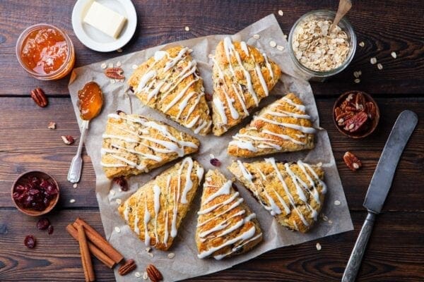 Scones with icing and nuts on a wooden table.