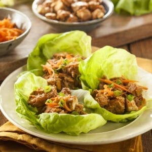 Asian lettuce wraps with chicken and carrots on a plate.