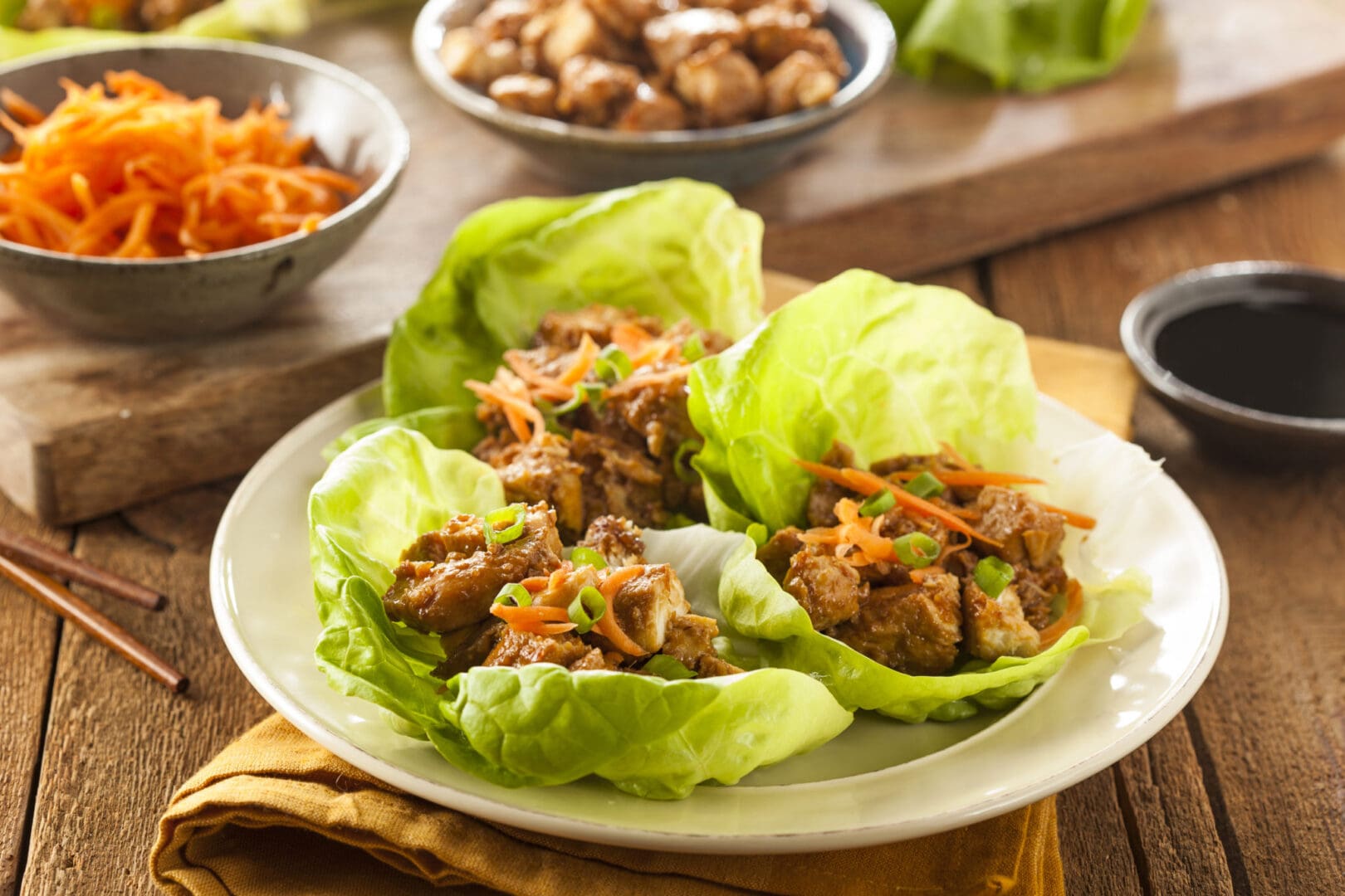 Asian lettuce wraps with chicken and carrots on a plate.