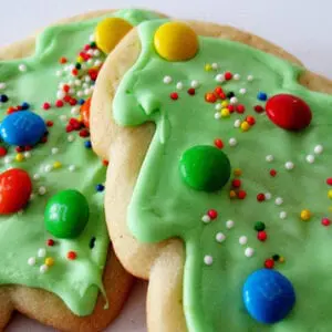 Two christmas tree cookies decorated with icing and m&m's.