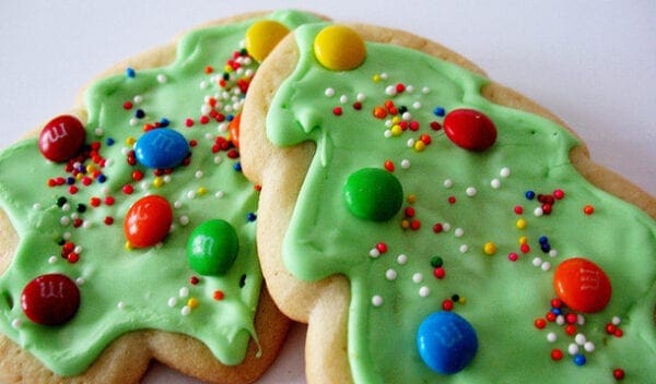 Two christmas tree cookies decorated with icing and m&m's.