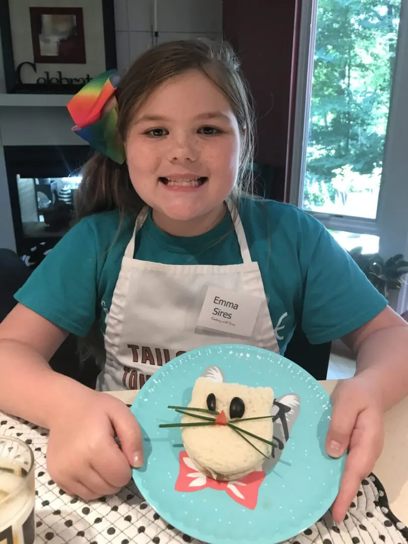 Toddler holding plate with a cat shape pastry