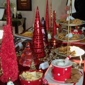 A christmas dessert table with red and gold decorations.