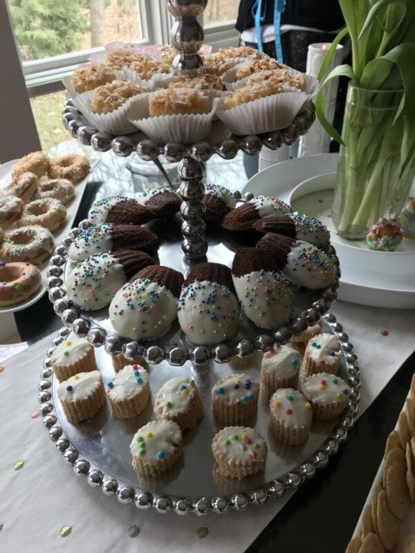 A three tiered cake stand filled with cupcakes and donuts.