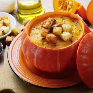 A bowl of soup on a wooden cutting board.