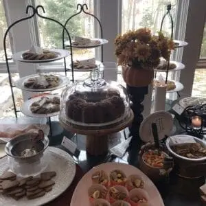 A table full of desserts on a table in front of a window.