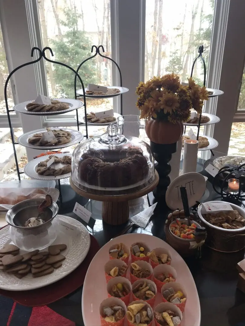 A table full of desserts on a table in front of a window.