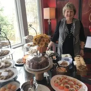 A woman standing in front of a table full of pastries.