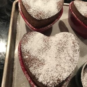 Three heart shaped cakes with powdered sugar on top.