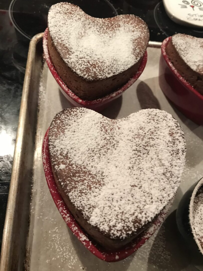Three heart shaped cakes with powdered sugar on top.