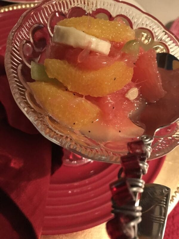 A glass bowl filled with oranges and a spoon.