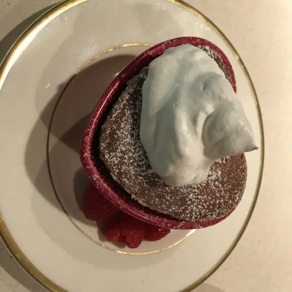 A dessert with whipped cream and raspberries on a plate.