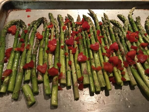 Roasted asparagus and red peppers on a baking sheet.