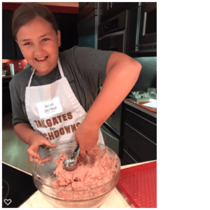 A girl in an apron is mixing ingredients in a bowl.